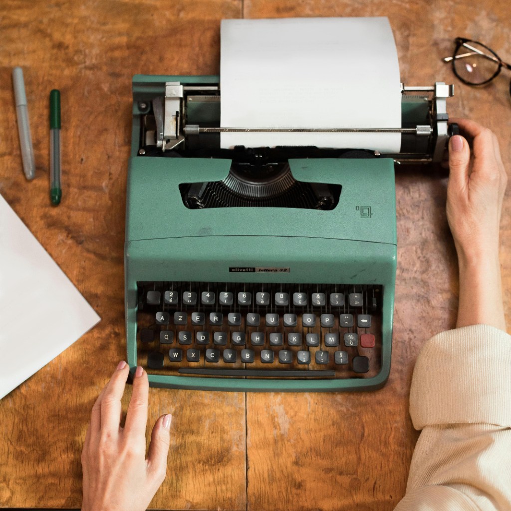 Retro green typewriter with woman hands typing. 